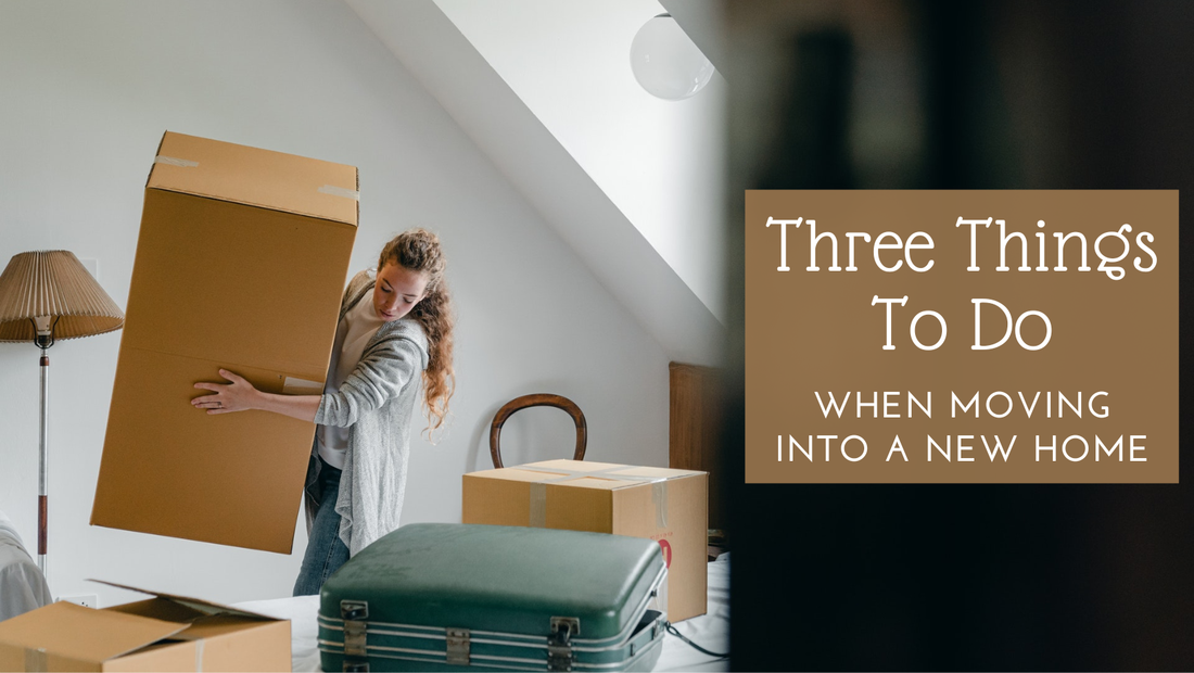 Three things to do when moving into a new home. Girl holding large moving box amidst luggage and boxes.
