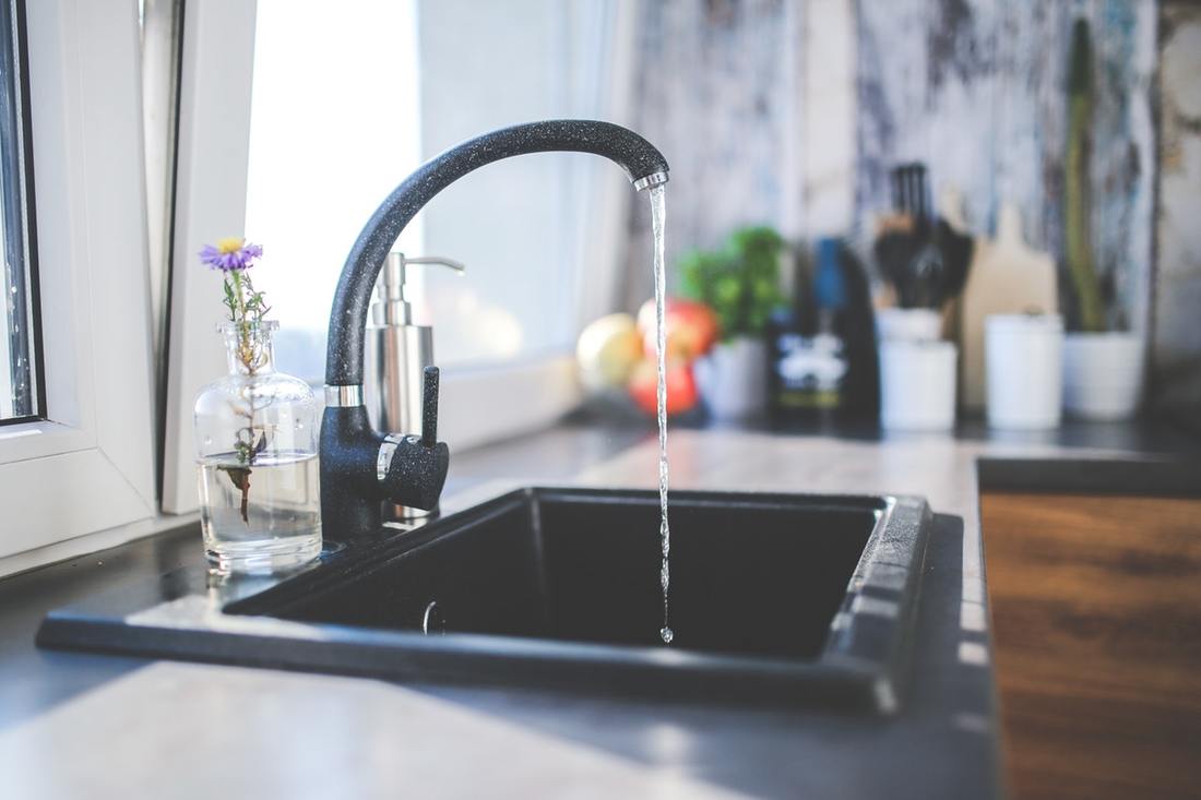 Black faucet and sink with running water in kitchen